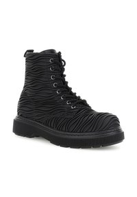 Bota alta negra con material texturizado de patrón ondulado, parte frontal con cordones, suela reforzada y ojales de metal.