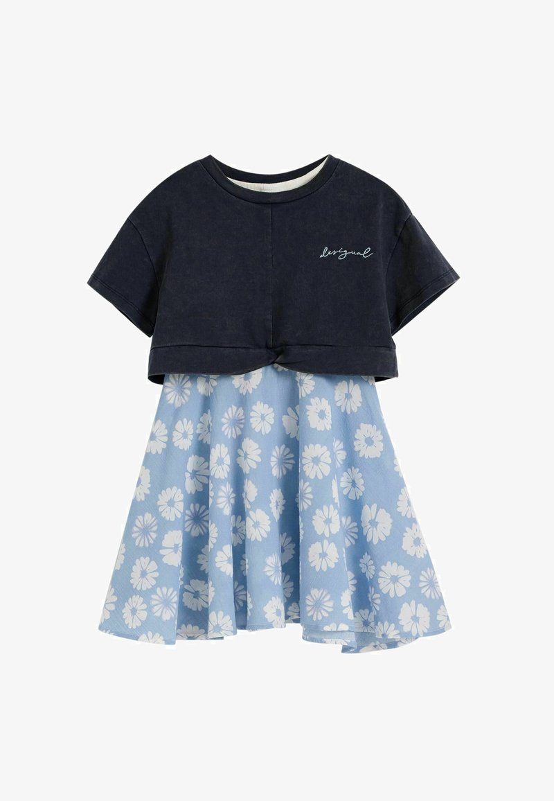 Rövid ujjú tengerészkék cropped felső kis fehér írott mintával, világoskék térdig érő szoknyával, mely fehér virágmintával van díszítve.