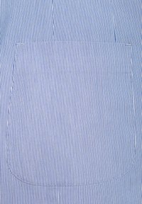 Pasiasty materiał w niebiesko-białym kolorze z kieszenią. Tekstura jest gładka, z pionowymi liniami, a szwy wokół kieszeni są widoczne.