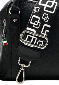Zwarte leren handtas met een zwarte en witte gestreepte schouderriem, zilveren hardware en een klein Italiaans vlaggetje eraan. 