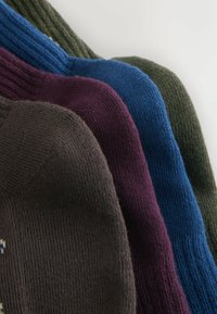 Četras adītas cepures, sakārtotas secībā: tumši brūna, burgundijas sarkana, zila un tumši zaļa. Katrai ir ribota tekstūra un mīksts izskats.