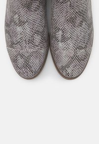 Bruna klackade ankelstövlar med ett texturerat mönster i lila och svart reptilhud. Rundad tå och släta sömmar.