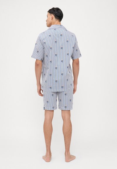 Pyjamas à rayures à manches courtes en marine et blanc, avec un imprimé ludique. Le matériau semble léger avec une coupe décontractée et un short.