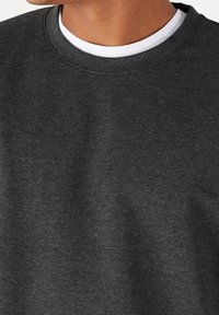 Sudadera gris oscuro con cuello redondo, hecha de un tejido texturizado. Presenta un ribete blanco en contraste visible en el cuello.