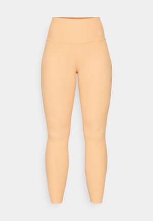 Leggings a vita alta e a costine di colore pesca. Presentano un design aderente e stretch senza hardware o motivi visibili.