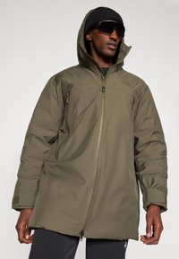 Giacca isolata verde oliva con zip frontale, cappuccio regolabile e due tasche laterali. Caratterizzata da una texture liscia e resistente.