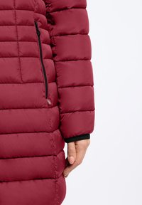 Bordeaux pufferjack met doorgestikte naden, voorzien van een ritszak opzij en zwarte elastische manchetten voor een veilige pasvorm.