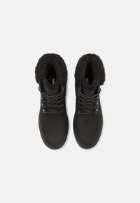 Botas negras hasta el tobillo con un exterior de cuero suave, forro de piel sintética en la parte superior y cordones en la parte delantera, con ojales de metal y una suela resistente.