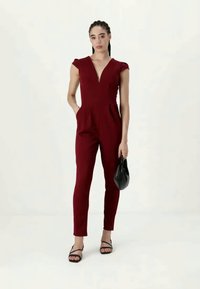 Burgundijas kombinezons ar dziļu V veida dekoltē, maziem piedurknēm un sašaurinātiem galiem. Izgatavots no gludas auduma, ar sānu kabatām un pieguļošu jostasvietu.