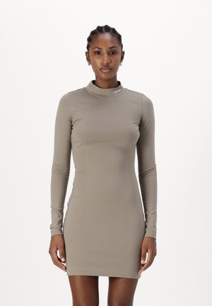 Robe ajustée à manches longues en tissu brun clair avec un col montant. Marque Calvin Klein sur le col. Texture lisse, design longueur genou.