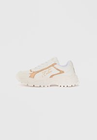 White athletic shoe with textured surface, gold accents, and a chunky sole. Features laces and brand detailing on the side.