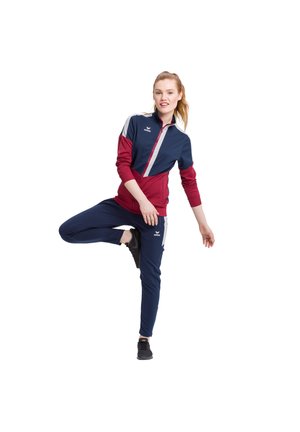 Sportieve trainingspak in marineblauw en bordeauxrood, met een ritsjack met grijze accenten en broeken. Stof is soepel; lichtgewicht ontwerp.