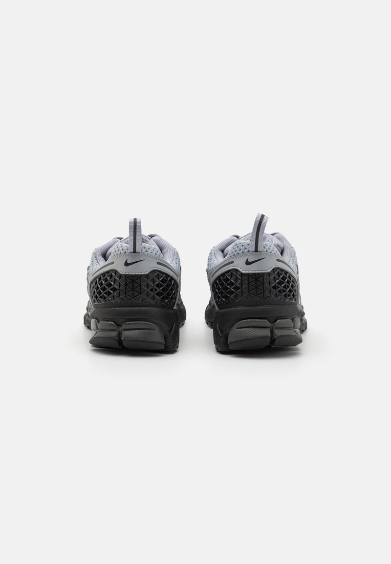 Nike-Sneaker mit grauem Mesh-Obermaterial und schwarzer Gummisohle. Hervorzuhebende Details sind strukturierte Akzente und Fersenlaschen.