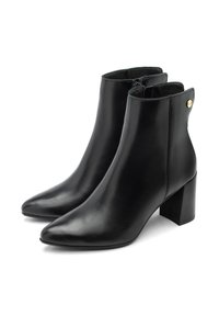 Mustat nahkaiset nilkkasaappaat, joissa on teräväkärkinen muoto ja paksu korko. Varustettu sivuvetoketjulla ja kultaisella yksityiskohdalla kannan lähellä. Sileäpintainen rakenne.