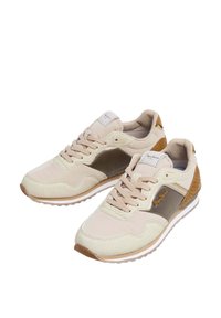 Beiga och bruna avslappnade sneakers med snören, texturerad detaljering och vita sålar, placerade i en vinkel på en vit bakgrund.