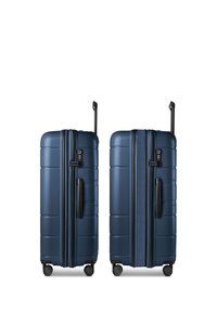 Deux valises rigides bleues avec poignées rétractables, quatre roues, poignées latérales et serrures à combinaison intégrées sur fond blanc.