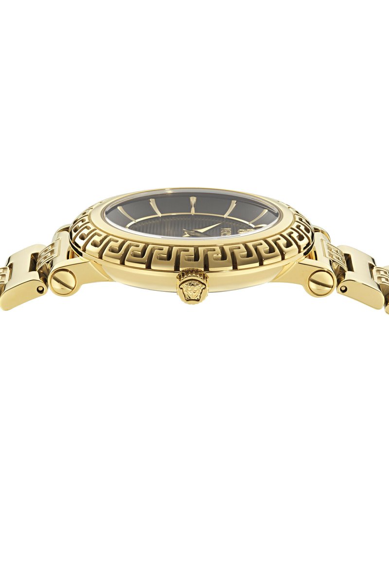 Goldene Armbanduhr mit schwarzem Zifferblatt, griechischem Schlüssel-Muster auf der Lünette und goldenem Medusen-Emblem auf der Krone, seitlich dargestellt.