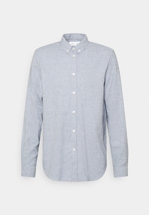 Chemise homme gris clair à manches longues, boutonnée avec col boutonné et boutons blancs, présentée sur un fond neutre.