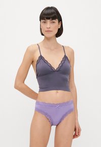 Šedý bralet s krajkovým lemem, tenkými ramínky a hlubokým V výstřihem; v kombinaci s levandulovými kalhotkami, které mají krajku a středový mašličkový detail.