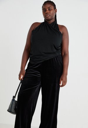 Black halter top made of soft fabric, paired with flowing black velvet wide-leg pants. Accessorized with a small, textured handbag.