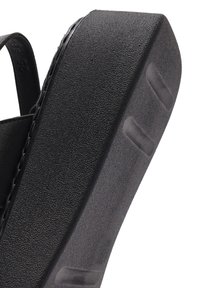 Black wedge sandal with textured upper, sturdy platform, and smooth sole. Features a contoured shape and minimal detailing on the straps.