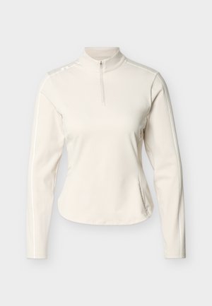 Kremfarget genser med lange ermer, halv glidelås foran, høy krage og subtil sømdetaljering på skuldrene og ermene.