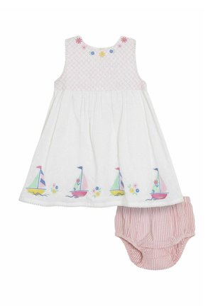 Vestido de algodón blanco con un cuerpo fruncido, con veleros y flores bordados, combinado con calzones rosa a rayas. Clásica forma en A.