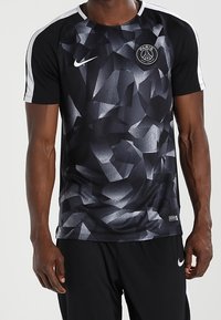 Czarna sportowa koszulka z geometrycznym wzorem w odcieniach szarości, z białymi akcentami na szwach ramion i okrągłym dekoltem.