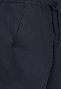 Navyblå byxor i vävt tyg, med en mjuk textur, framfickor och justerbar dragsko i midjan med knappstängning.