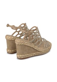 Sandali con zeppa beige con cinturini incrociati e dettagli luccicanti. Presentano una finitura in juta intrecciata sul tallone e una fodera interna liscia.