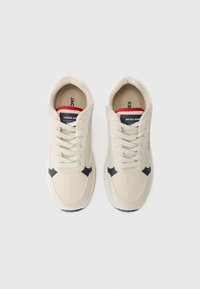 Beige sneakers with mesh and synthetic leather upper, navy accents, round toe, flat lace-up design, and textured outsole.