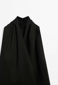 Schwarzes Kleidungsstück aus einem strukturierten Stoff. Verfügt über ein Wickeldesign und einen stehenden Kragen. Die Oberfläche zeigt einen dezenten Glanz, der ein anspruchsvolles Erscheinungsbild schafft.