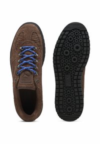 Brūnas zamšādas pārgājienu kurpes ar zilām auklām, ar teksturētu augšpusi un melnu gumijas zoli ar rakstainu protektoru dizainu.