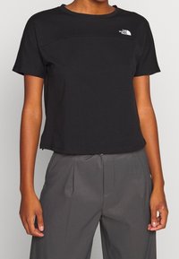 Mustat lyhythihaiset T-paidat, jotka on valmistettu kevyestä kankaasta, pyöreä kaula-aukko ja valkoinen logo vasemmassa yläkulmassa. Lyhennetty malli.