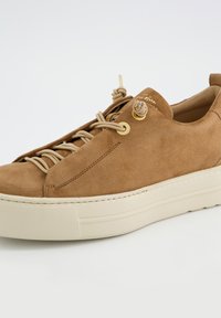 Baskets en daim marron avec un bout rond, une semelle en caoutchouc de couleur crème, et un système de laçage décoratif avec des œillets et accents dorés.