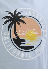 Világoskék póló kör alakú mintával, fekete pálmafával, naplemente színátmenettel és fehér "Jack & Jones California" felirattal.