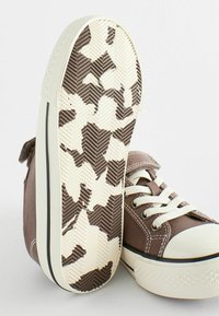 Ruske kanvas sneakersi s bijelom gumiranom čepom i okomitim rupicama. Tekstura donjeg dijela sadrži smešasti i kremasti kamuflažni uzorak.