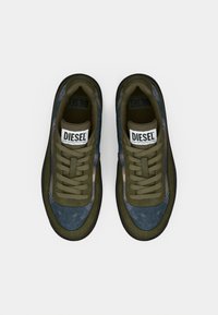 Sneakers verde oliva con tomaia in tessuto strutturato, presentano un pannello accentuato blu, colletto imbottito e lacci tono su tono. Suola in gomma nera.