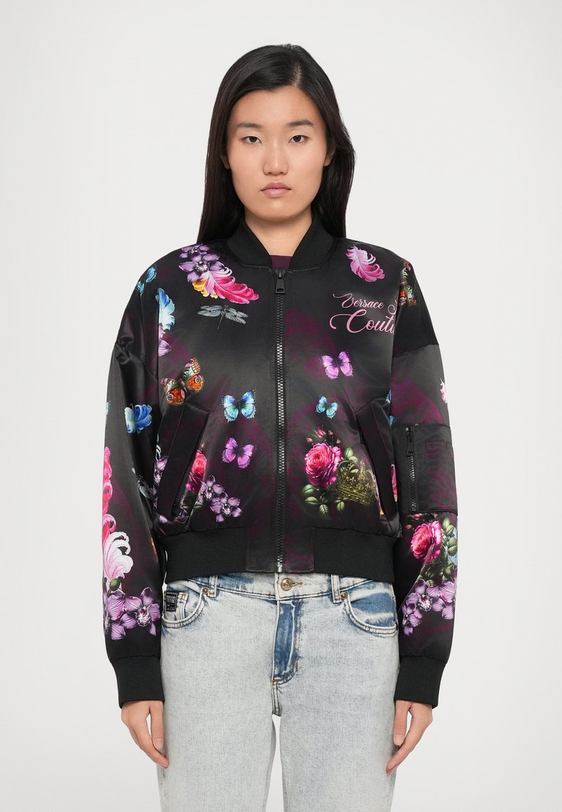 Čierna bomber bunda s živými kvetinovými a motýlími vzormi, so zapínaním na zips, ribbed manžetami a uvoľneným strihom, vyrobená z hladkej tkaniny.