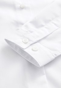 Weißes Hemdärmelt mit zwei weißen Knöpfen, glatter Textur, sauber genähten Kanten und einem klassischen Design ohne sichtbare Muster.