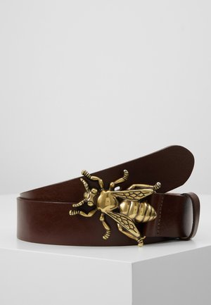 Ceinture en cuir brun avec une boucle en forme d'abeille dorée, présentant des ailes détaillées, des antennes et une texture corporel, créant ainsi un point focal distinct.