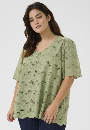 Zielona bluzka z krótkim rękawem i dekoltem w serek, ozdobiona haftowanymi wzorami kwiatowymi, z falbankowanym dołem i guzikami, wykonana z lekkiego materiału.