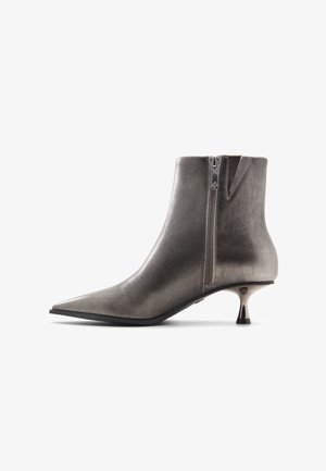 Metallisch grauer Knöchelstiefel mit einer spitzen Zehe, seitlichem Reißverschluss und einem einzigartigen skulpturalen Absatzdesign. Glatte Textur mit einem eleganten Finish.