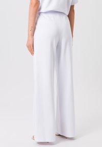 Weiße, weite Hosen aus einem glatten Material mit elastischem Bund. Anmutiger Fall, minimalistische Details, geeignet für Freizeit- oder formelle Anlässe.