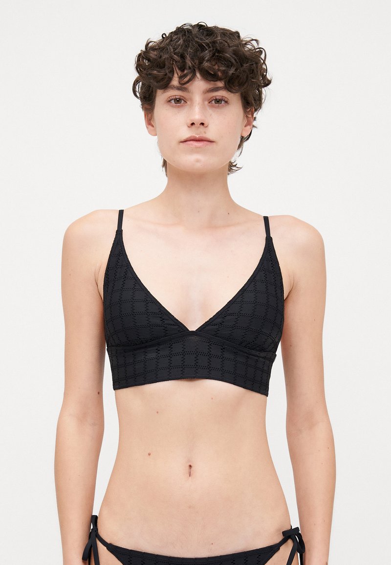 Zwarte bralette met een V-halsontwerp, voorzien van een gestructureerd ruitpatroon, verstelbare dunne banden en een brede band onder de buste.