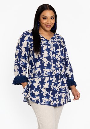 Blouse bleu et crème avec un motif floral, décolleté en V et manches trois-quarts avec des franges marines aux poignets.