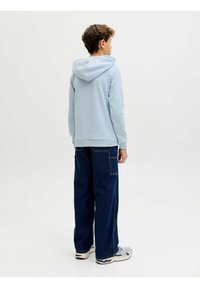 Sudadera con capucha azul claro de textura suave, combinada con vaqueros de pierna ancha azul oscuro con bolsillos laterales y un corte relajado.