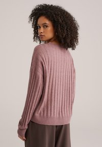 Roze geribbelde gebreide trui met een losse pasvorm, voorzien van lange mouwen en een ronde hals. Geheel met een gestructureerd stofpatroon.