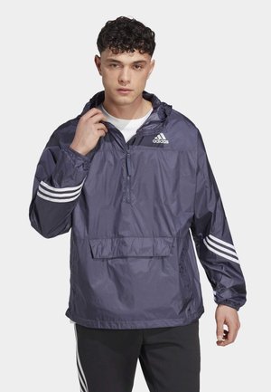 Chaqueta rompevientos navy con media cremallera, bolsillo delantero, puños elásticos y acentos en blanco de tres rayas en las mangas. Fabricada con material ligero.