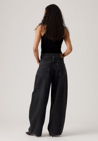 Zwarte denim jeans met een hoge taille en wijde pijpen. Beschikt over grote achterzakken, een tan leren label en een zachte stofstructuur.
